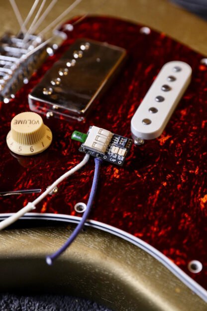 Treblemaker positioned on the tortoiseshell pickguard of a Strat-style guitar, fully wired and ready to be installed.