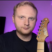 Picture of Ben Marshall founder of mars-tronic holding a guitar with a purple background.